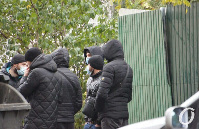 люди в черном возле забора