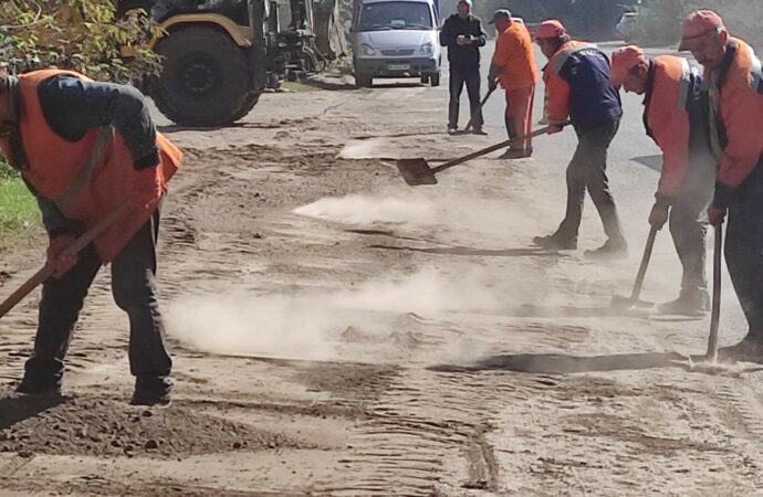 рабочие ровняют дорогу