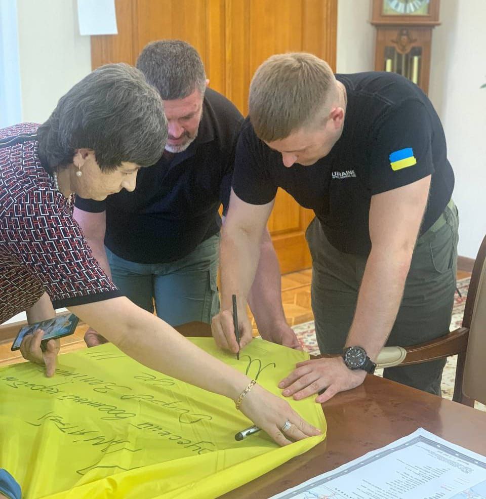 Марченко подписывает послание на флаге