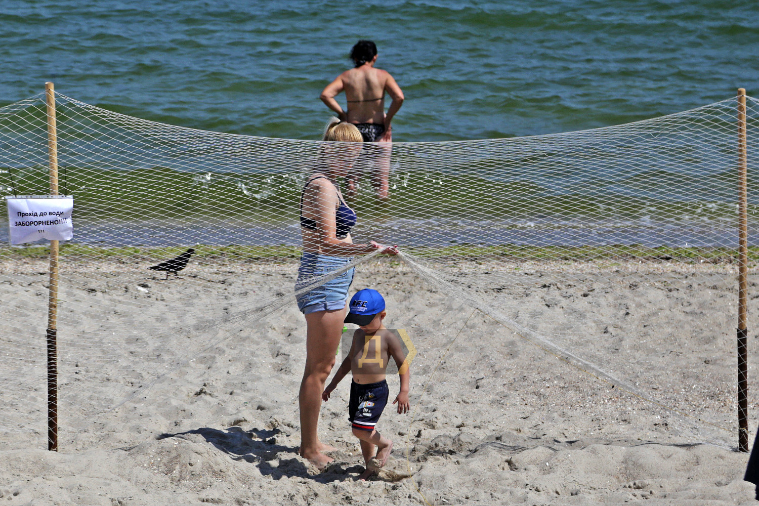ребенок на пляже проходит под забором