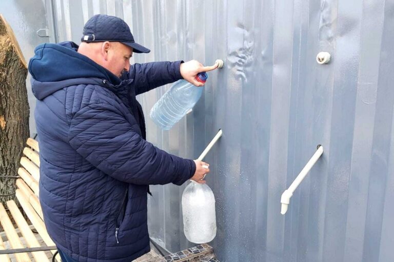 мужчина набирает воду в бювете