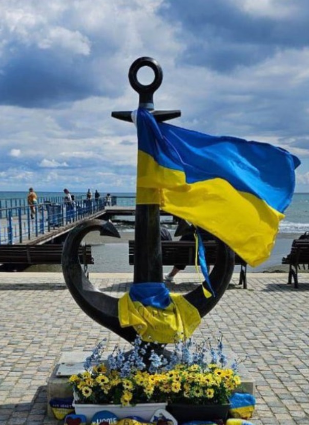 Якорь-сердце с украинским флагом на нем.