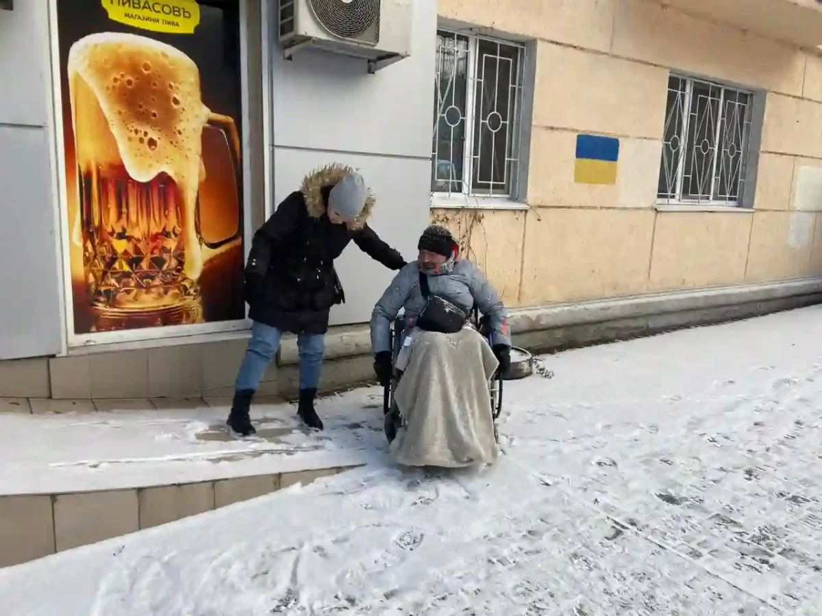 Жінка допомогає чоловіку у кріслі колісному