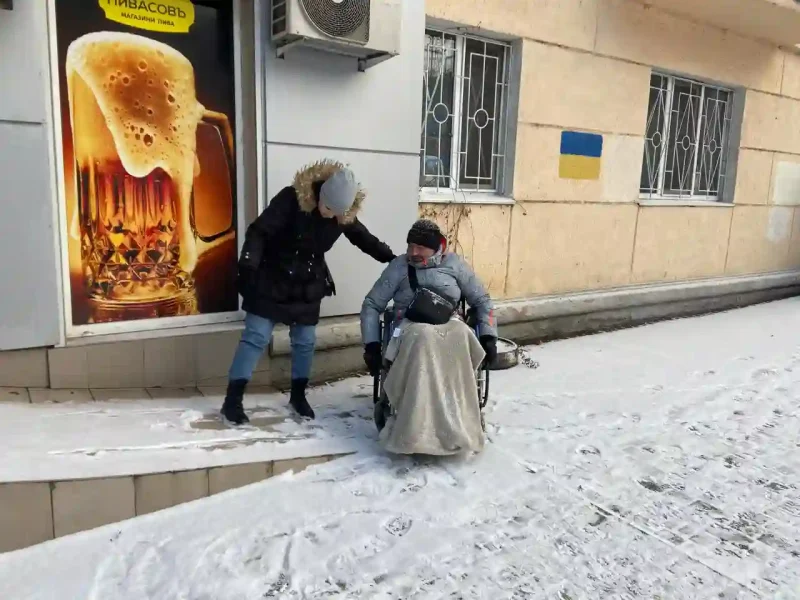Жінка допомогає чоловіку у кріслі колісному