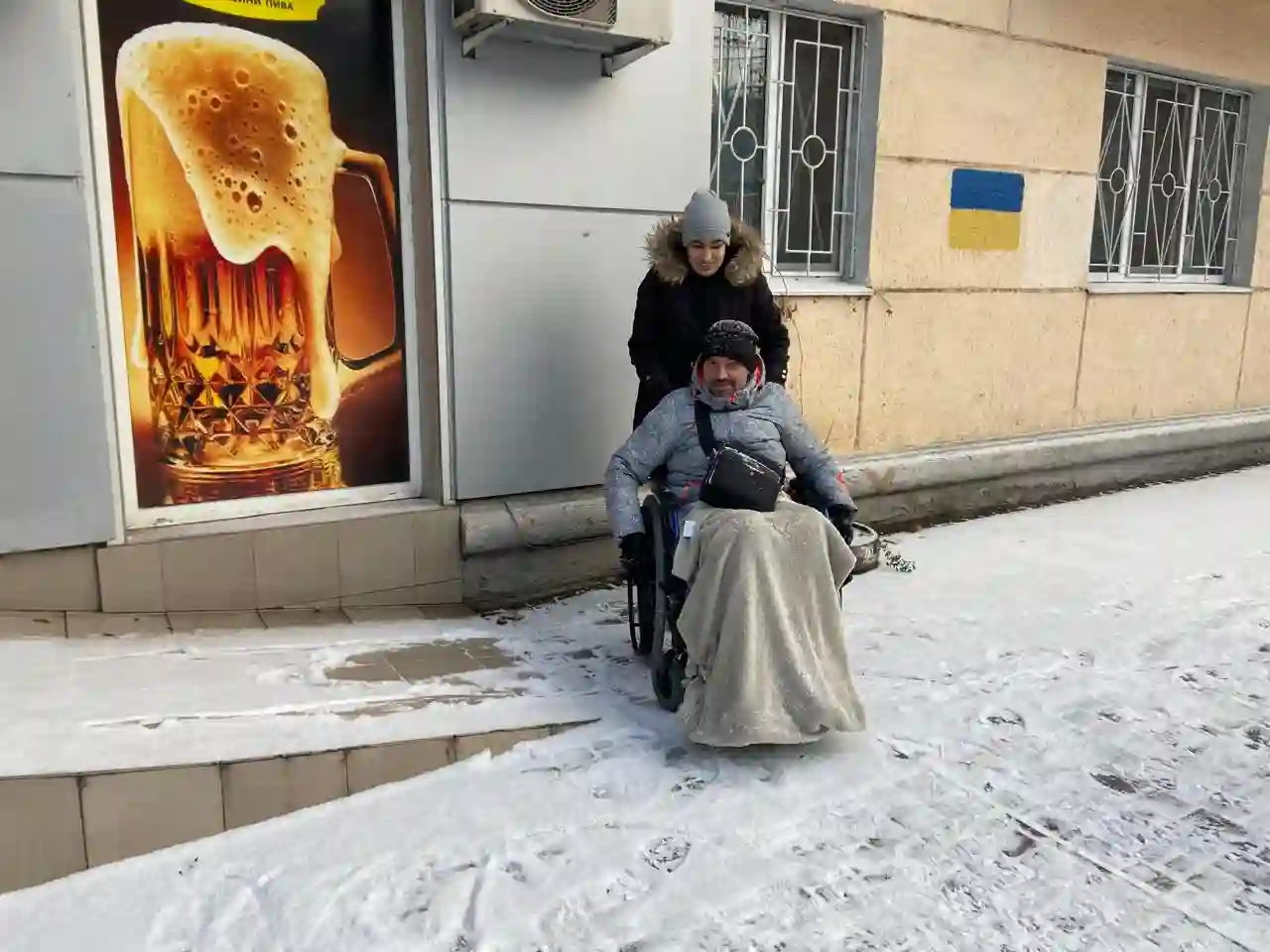 Жінка допомогає чоловіку у кріслі колісному