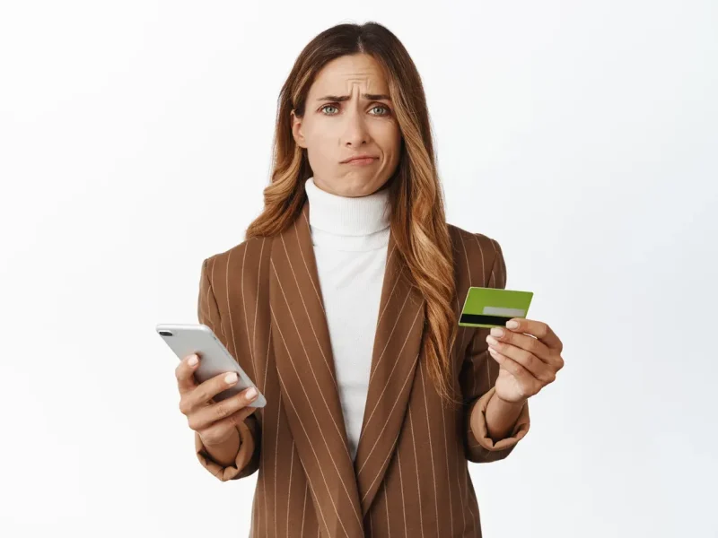 Молода жінка з телефоном та банківською карткою