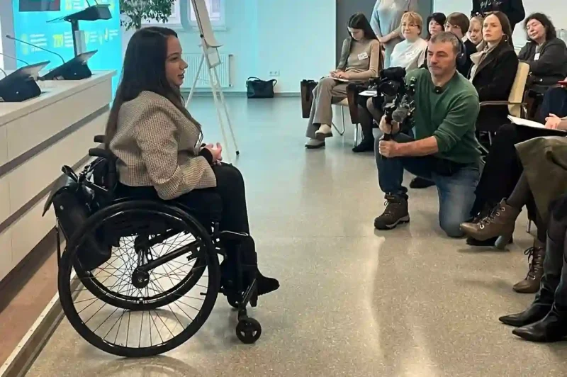 Тренінг з безбар’єрності для працівників банку: спікерка на кріслі колісному спілкується з учасниками під час навчальної сесії.