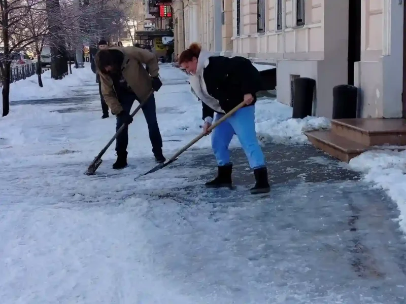 Комунальники прибирають лід на тротуарі в центрі Одеси під час відлиги
