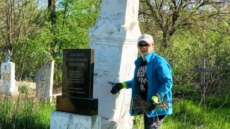 Жінка прибирає цвинтар у Соборному
