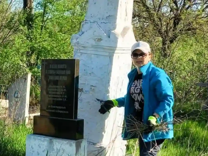 Жінка прибирає цвинтар у Соборному