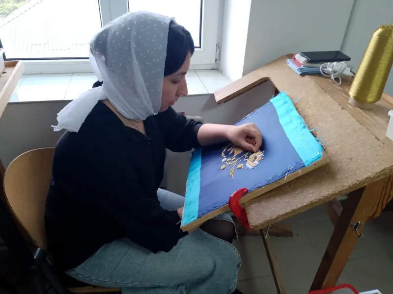 Марійка зосереджена на роботі з вишивання