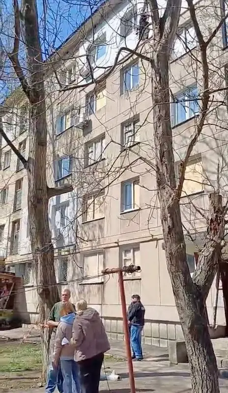 Одесити стоять біля пошкодженої багатоповерхівки, обговорюючи наслідки нічної атаки