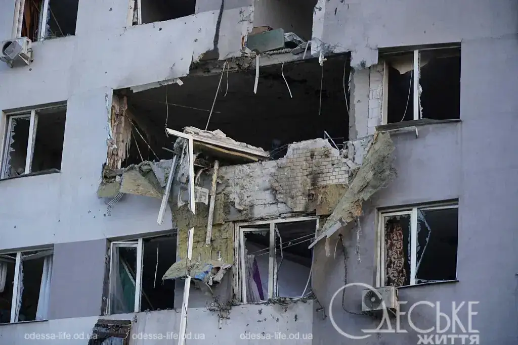 Крупный план дыры в бетонной стене многоэтажного дома после попадания шахеда.