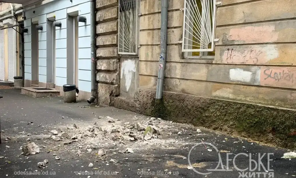 Осыпавшиеся куски ракушняка и штукатурки на асфальте возле фасада дома на Успенской